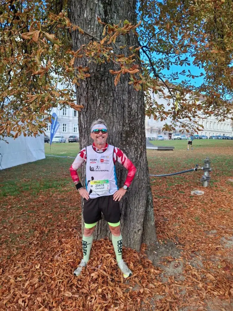Christof mit Startnummer 20478 steht vor einem Baum im Herbstlaub in Wien